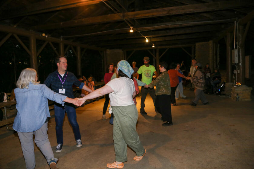 People square dancing in a pavilion at night